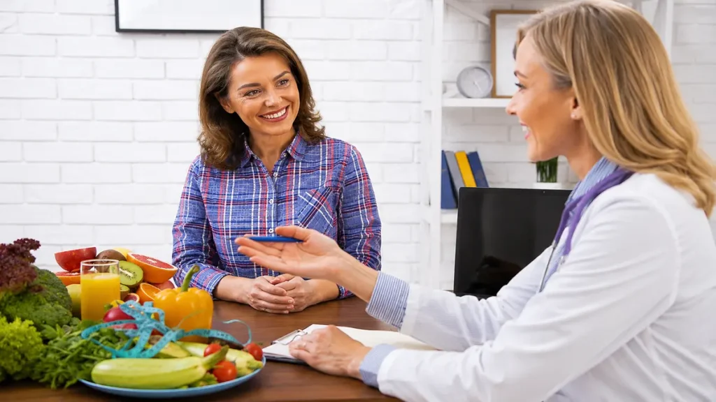 Mature woman smiling during a nutritionist consultation with fresh fruits and vegetables on the desk.