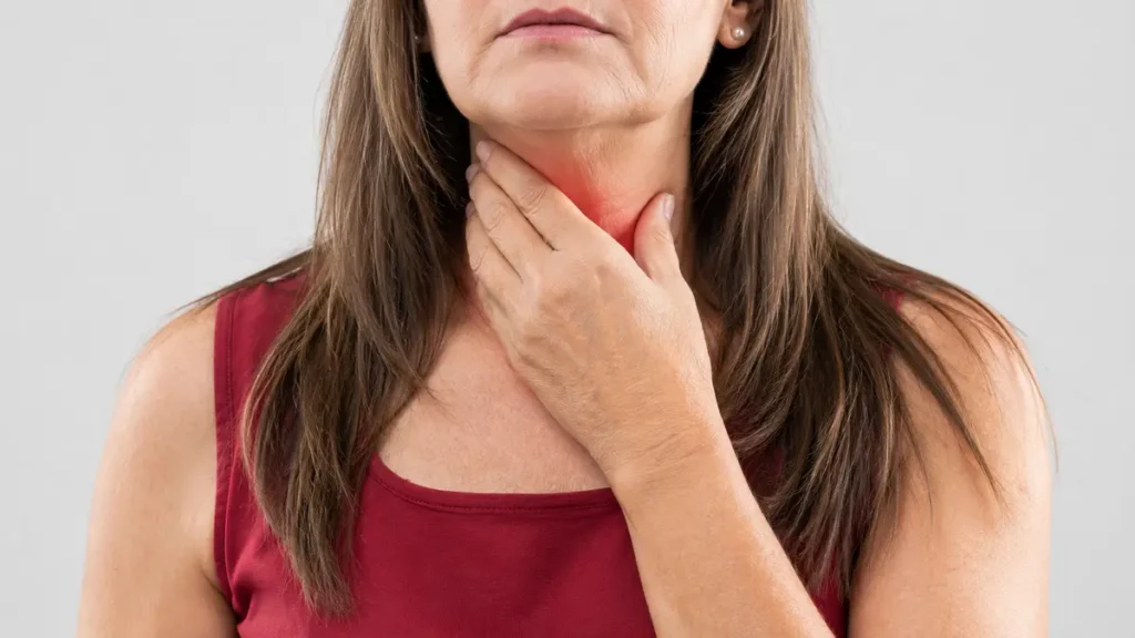 Midlife woman holding her hand to her throat area while considering a medical thyroid panel to rule out functional mimics of hypothyroidism after 50.