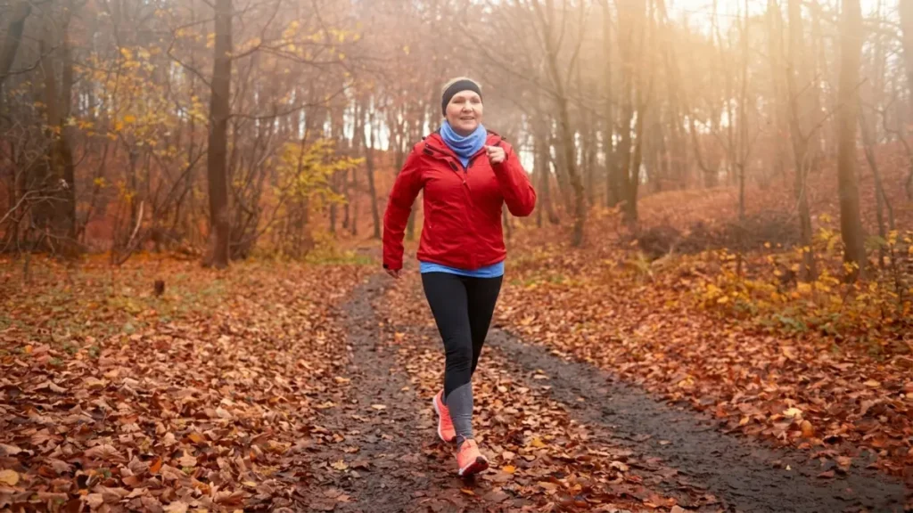 An active woman walks briskly along an autumn forest path to support hormonal balance and maintain her basal metabolic rate.