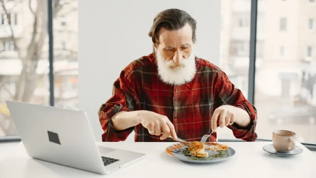 An older man eating a protein-rich meal, illustrating why meeting protein thresholds at every meal matters for muscle recovery after 50.