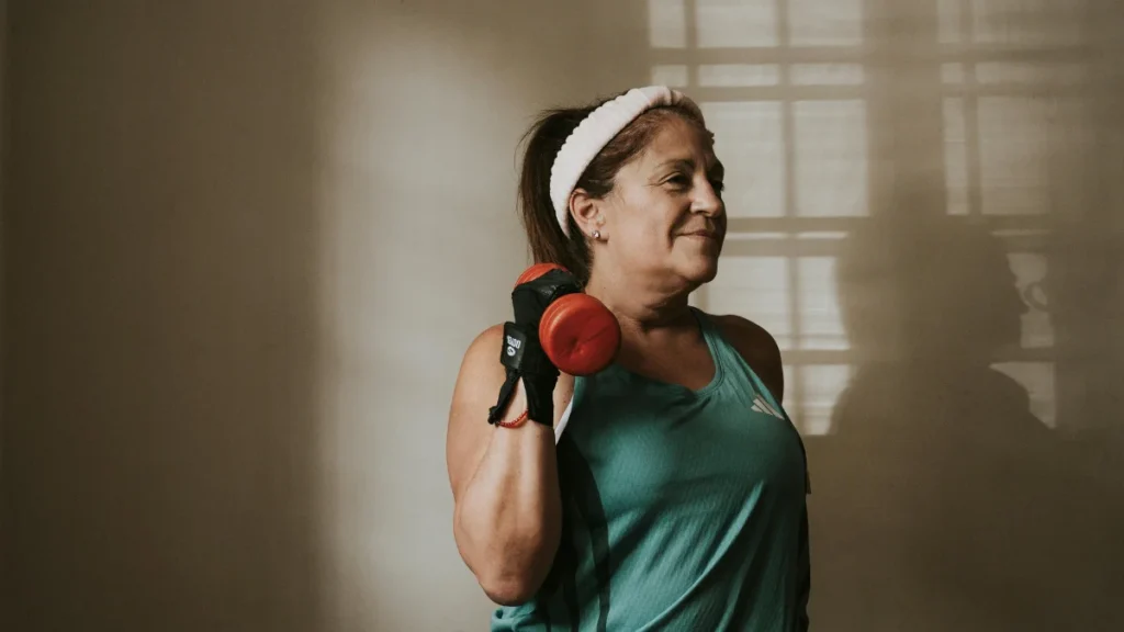 Fit woman over 50 doing strength training with a dumbbell, representing high-intensity exercise for cellular health and autophagy