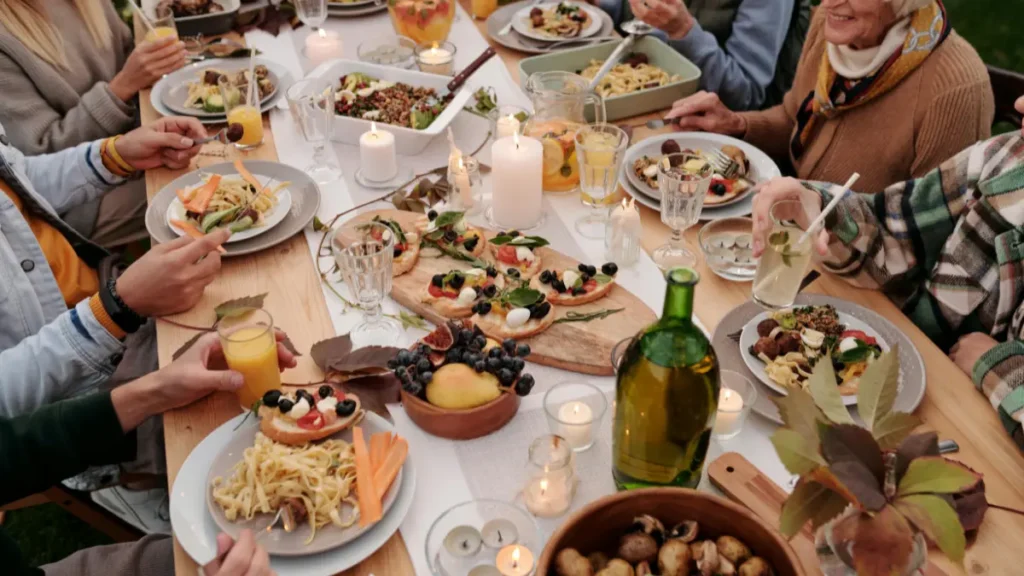 Older adults sharing an early outdoor dinner with fresh healthy food, supporting the habit of finishing meals before late evening.