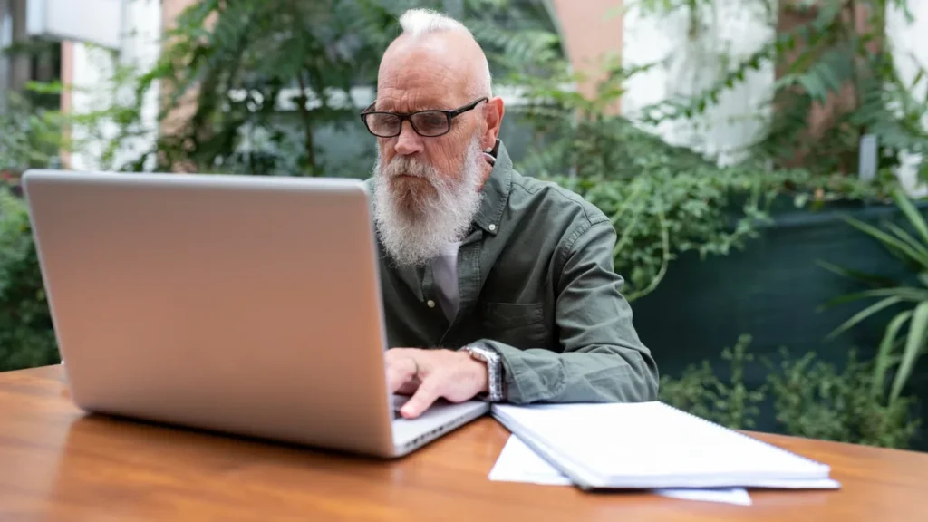 Active older man focused on a computer screen to monitor consistency in reaction time brain health after 50.