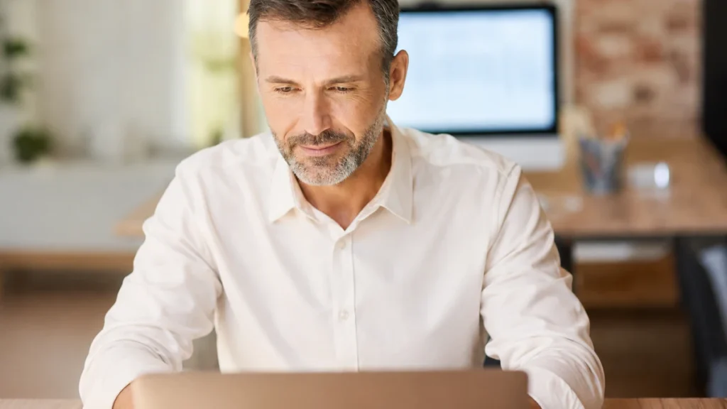 A mature man reviewing his digital health biomarkers on a tablet in a bright room, bridging clinical data and personal diagnostics.