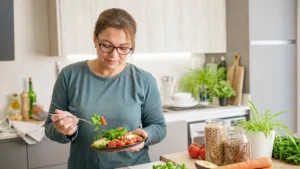 A thoughtful mature woman looking at a healthy salad in a bright kitchen, questioning her overall nutrient absorption after 50.