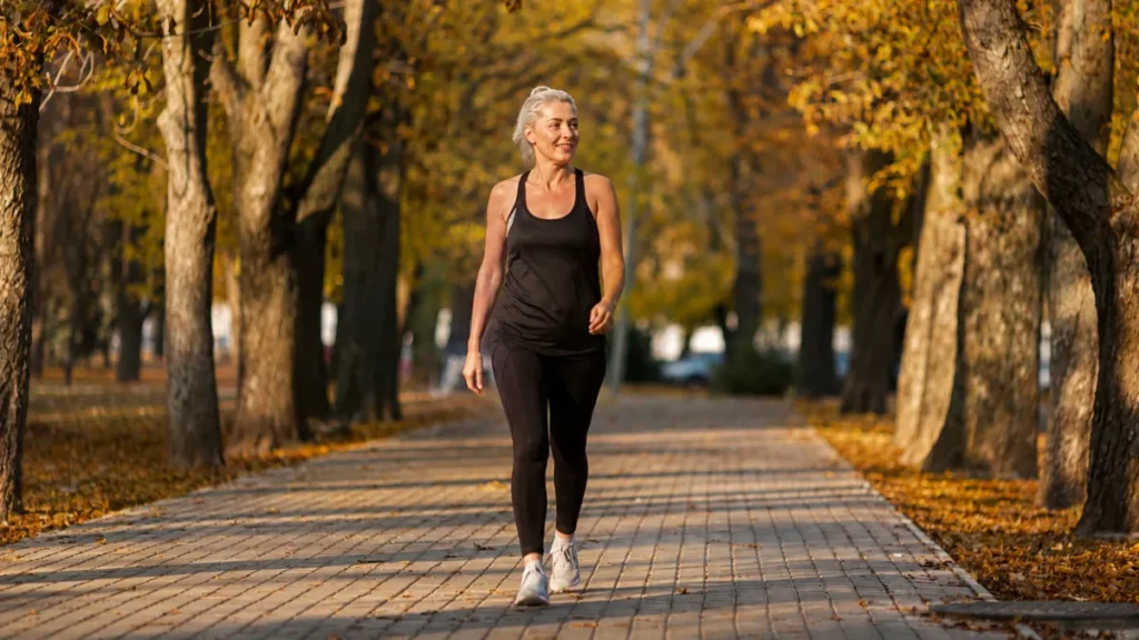 Active woman walking on a sunlit park path to support healthy daily brain signal processing.