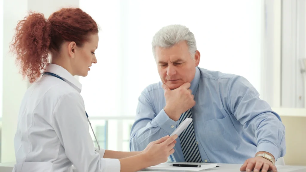 Older man reviewing health information with his doctor during a routine medical consultation.