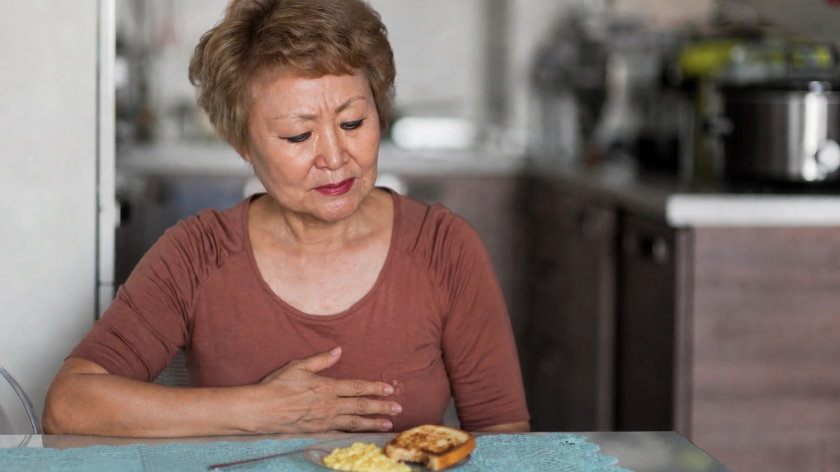 Mature women at the breakfast table, visibly uncomfortable with bloating after meals despite no change in diet