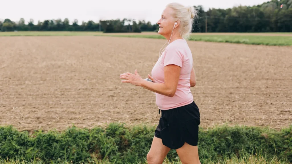 Active mature woman power-walking on a rural trail to absorb bright morning outdoor light and reset her daily rhythm.