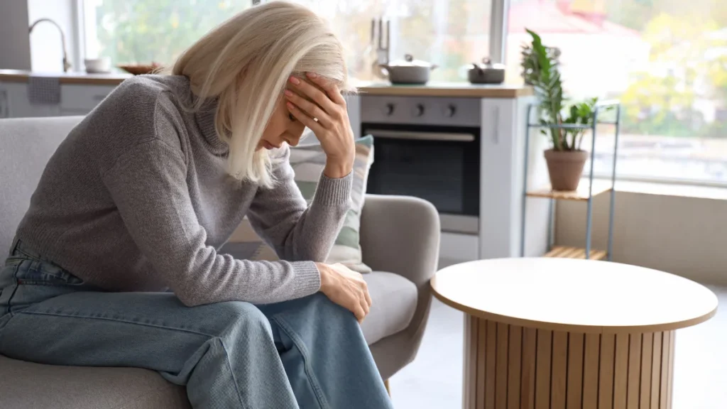 Mature woman resting her head on a couch to manage day-after exercise exhaustion.