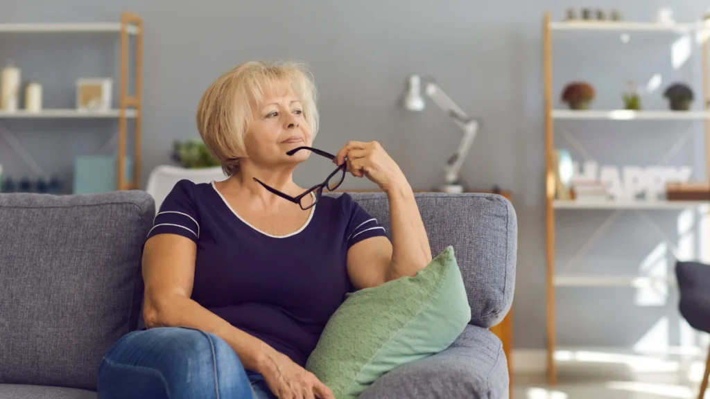 Mature woman sitting quietly at home, illustrating the early stages of social withdrawal linked to hearing difficulties.