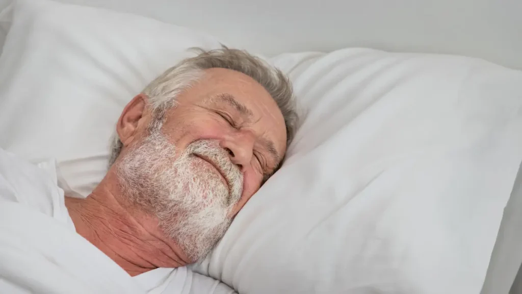 Older man sleeping peacefully at night, illustrating the deep sleep period when the body naturally releases most of its growth hormone after age 50.