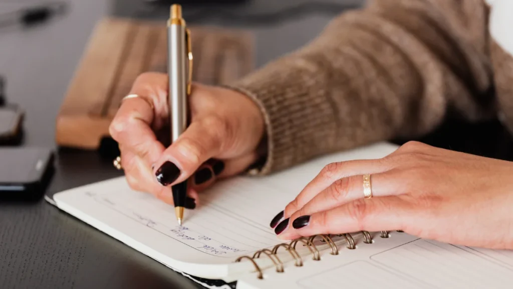 Hand of an older woman writing in a journal, practicing expressive writing to support immune function after loss.