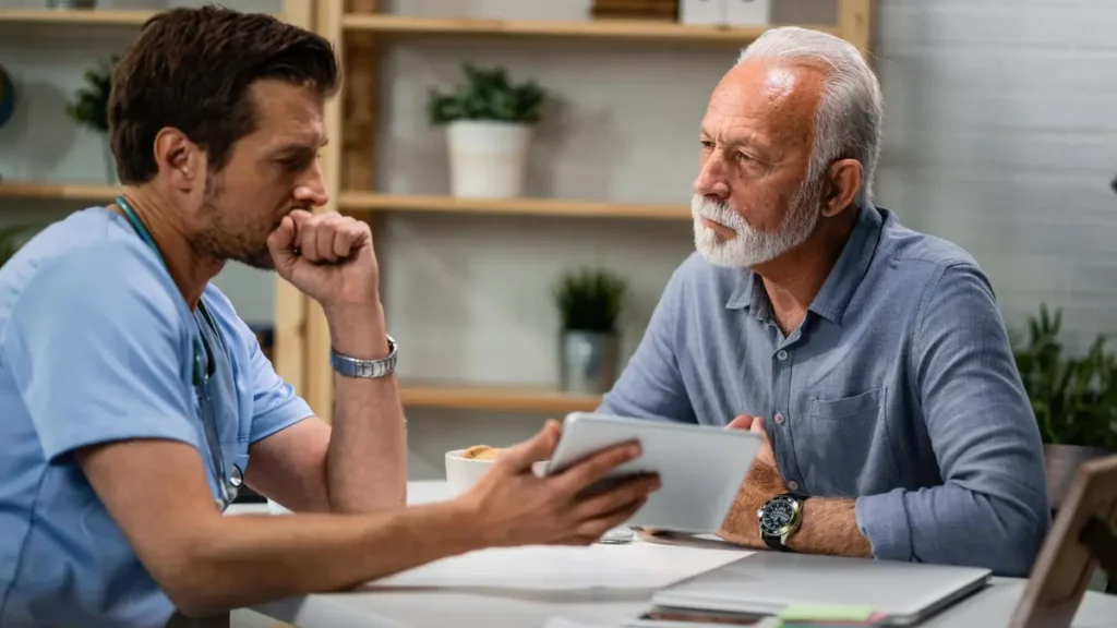 Older man discussing medication interactions with his doctor before adding a magnesium supplement.