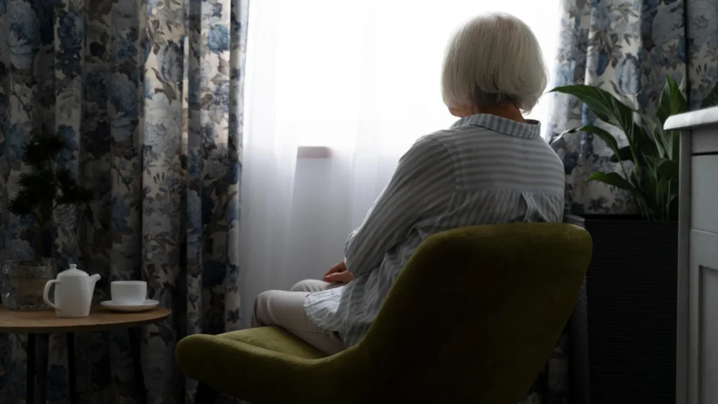 Retiree sitting alone by a window with no clear task for the day.