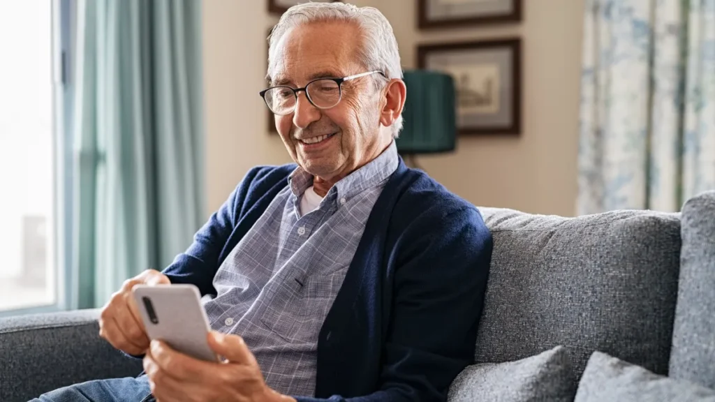 Mature adult smiling while choosing a contact to call from their phone.