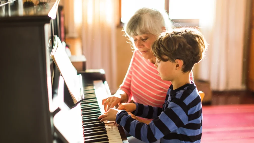 Grandmother teaching her grandson piano, the kind of engaged purpose linked to sharper thinking later in life.