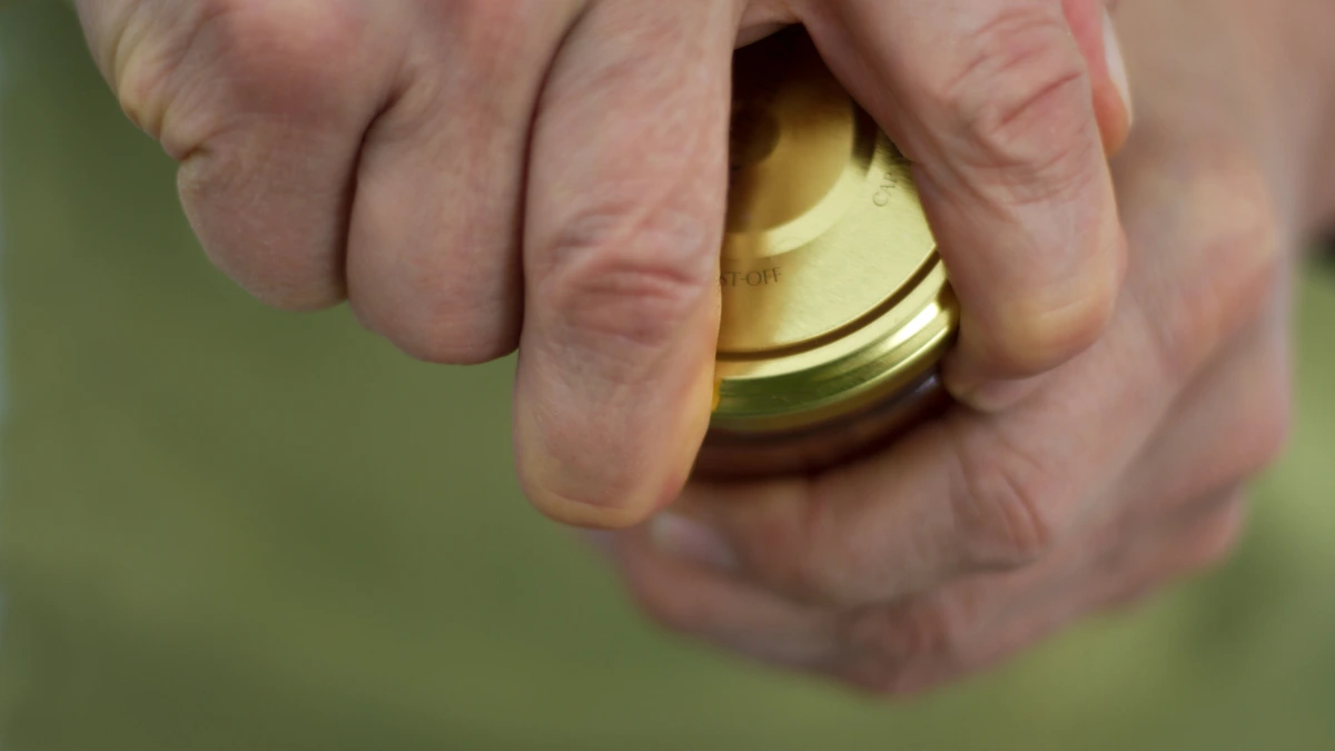 Close-up of hands gripping and twisting open a stubborn jar lid, showing the everyday effort used to test grip strength.
