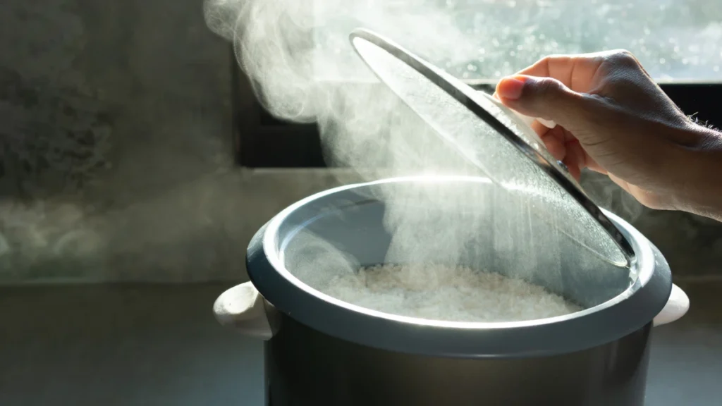 Steam rising from a pot as the lid is lifted in a home kitchen, showing moist low-heat cooking as a joint-friendly alternative to dry heat methods.